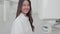 A smiling woman doctor in a white coat looks at the camera in a close-up image. At the x-ray room, a confident, skilled, and
