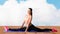 Smiling woman doing splits on mat over cloud