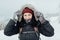 Smiling woman dressed warm holding her hood with snowy gloves