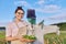 Smiling woman farmer with basket hugging scarecrow in vegetable garden