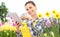 Smiling woman in garden of flowers daffodils touch screen of digital tablet, spring concept and internet search