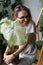 Smiling woman gardener holding embracing flower - caladium houseplant with large white leaves in clay pot