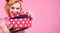 Smiling woman with gift box. Beautiful girl with present box. Woman in red dress opening pink box with spots. Present