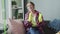 Smiling woman in gloves sitting on sofa, relaxing after house cleaning work