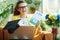 Smiling woman with graduation cap and laptop showing textbook