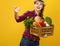 Smiling woman grower with box of fresh vegetables beckoning