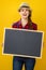 Smiling woman grower isolated on yellow showing blank board