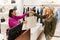 Smiling woman handing bag with clothes to customer in boutique