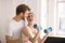 Smiling woman having a workout with dumbbells together with her husband and looking enjoyed
