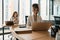 Smiling woman with headphones works at laptop, employee sits behind