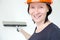 A smiling woman in a helmet holds a putty knife. Repair in the apartment. Quick repair. Repair Tips. copy space