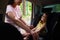 Smiling woman with her cute daughter looking at each other while mother fastening her daughter with seatbelt on the child car seat