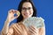 Smiling woman holding bitcoin coin and american dollar bills in her hands closeup