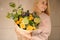 Smiling woman holding a bouquet of tender bright yellow roses