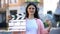 Smiling woman holding clapperboard and bunch of dollars, high-paid occupation