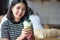 Smiling woman holding matcha green tea latte in the morning at coffee shop. Asian girl holding green tea glass in cafe
