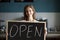 Smiling woman holding open sign chalkboard inviting to new cafe