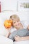 Smiling woman holding an orange piggy bank