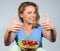 Smiling woman holding raspberries and showing thumb up gesture