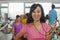 Smiling woman holding stopwatch in foreground, people working out in the gym in the background