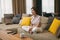 Smiling woman homeowner tenant sitting on sofa in cozy living room watching television, resting on weekend