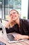 Smiling woman with laptop sitting at cafe looking up