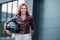 smiling woman in leather jacket holding motorcycle helmet on street