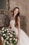 Smiling woman in long dress holds basket of flowers