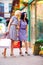 Smiling woman looking in shop window, colorful exterior