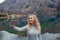 Smiling woman makes selfie at the mountain lake