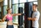 Smiling woman with personal trainer boxing in gym