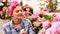 Smiling woman with pink handkerchief watered pink flowers. Woman cares for hydrangea in the summer. Concept of gardening