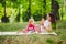 Smiling woman play and sit on green grass in park, rest and hug hold soap bubble blower with little cute child baby girl. Happy