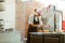 Smiling woman pours powdered sugar onto fresh buns at table in craft bakery shop