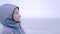 Smiling Woman in raincoat under the rain on gray cloudy beach, cold day