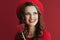 smiling woman in red dress and beret against red background