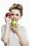 Smiling woman with red and green apples in her hands. Beautiful blonde in a gray t-shirt. Healthy plant food and vitamins. White