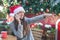 Smiling woman in Santa hat talking on her phone in cafe outside, pointing