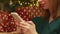 Smiling woman sending Christmas greetings sitting under the Christmas tree with wrapped gifts