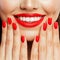 Smiling woman showing her hand with manicured nails. Red nail polish and makeup lips with bright red color tint lipstick