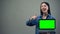 Smiling woman showing thumbs-up holding green screen laptop, online education