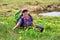Smiling woman sits on blooming alpine lawn