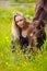 Smiling woman sits in the meadow with her arabian horse