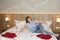 Smiling woman sitting on bed in hotel room, vacation concept