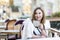 Smiling woman is sitting in a cafe. Brunette in a white jacket. Close-up