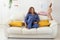 Smiling woman sitting on comfortable coach in living room in pajama and her child daughter - homewear and free time