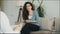 Smiling woman sitting on couch and talking to female psychoanalyst in her office indoors