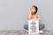 Smiling woman sitting on the floor with motivational board