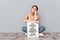 Smiling woman sitting on the floor with motivational board