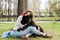 Smiling woman sitting on the ground and hugging tibetan mastiff dog outdoors. Girl and dog playing in park